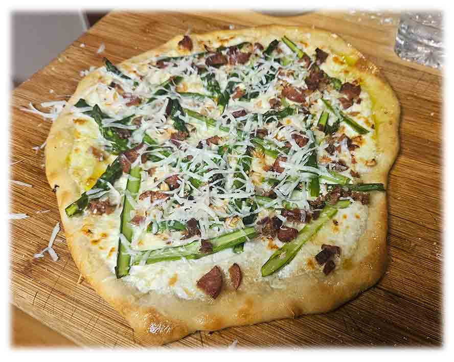 Nicely browned finished Flammenkuchen with asparagus. 
